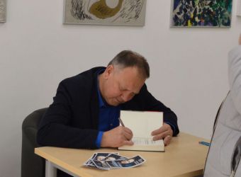 Zdjęcie Cezarego Łazarewicza podpisującego książki w Galerii Zagłębiowskiej Mediateki